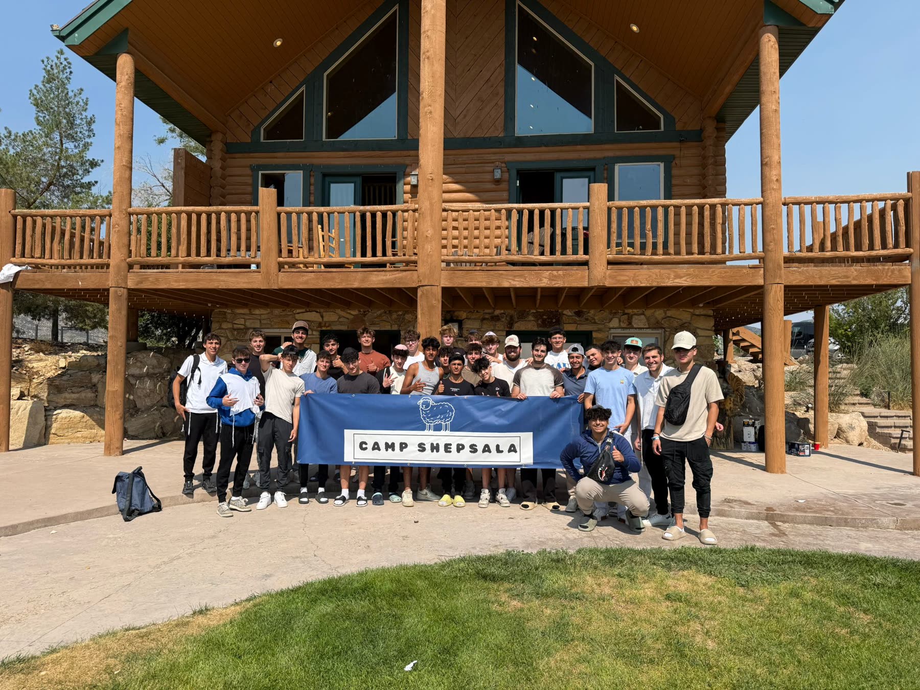 Camp Shepsala group photo with camp banner in front of the lodge
