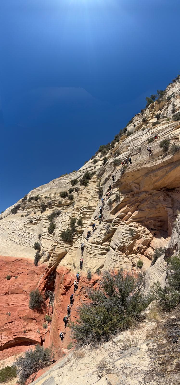 Line of hikers along a dramatic red rock canyon