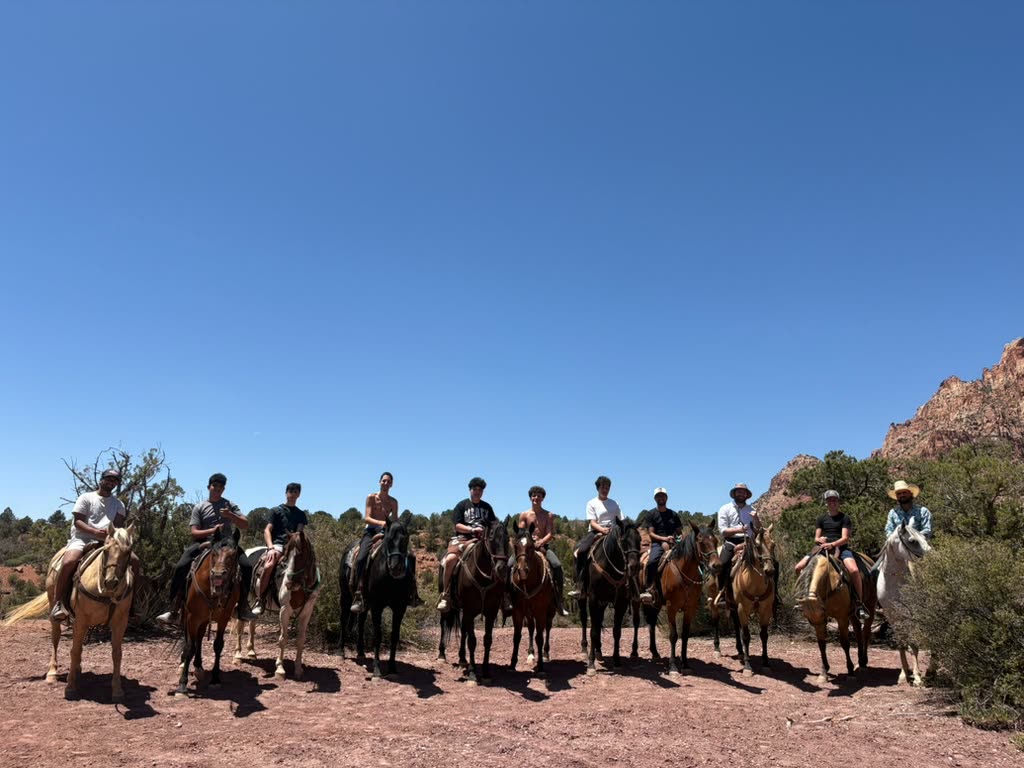 Guys riding horses through the desert