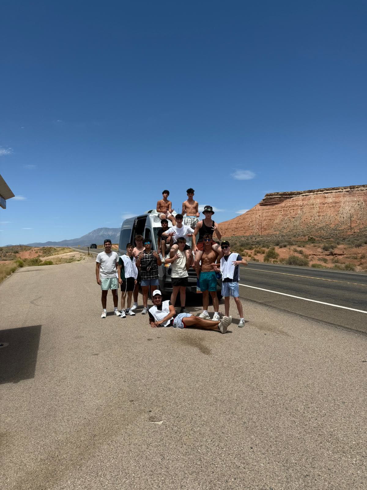 Group posed on top of a van in the desert